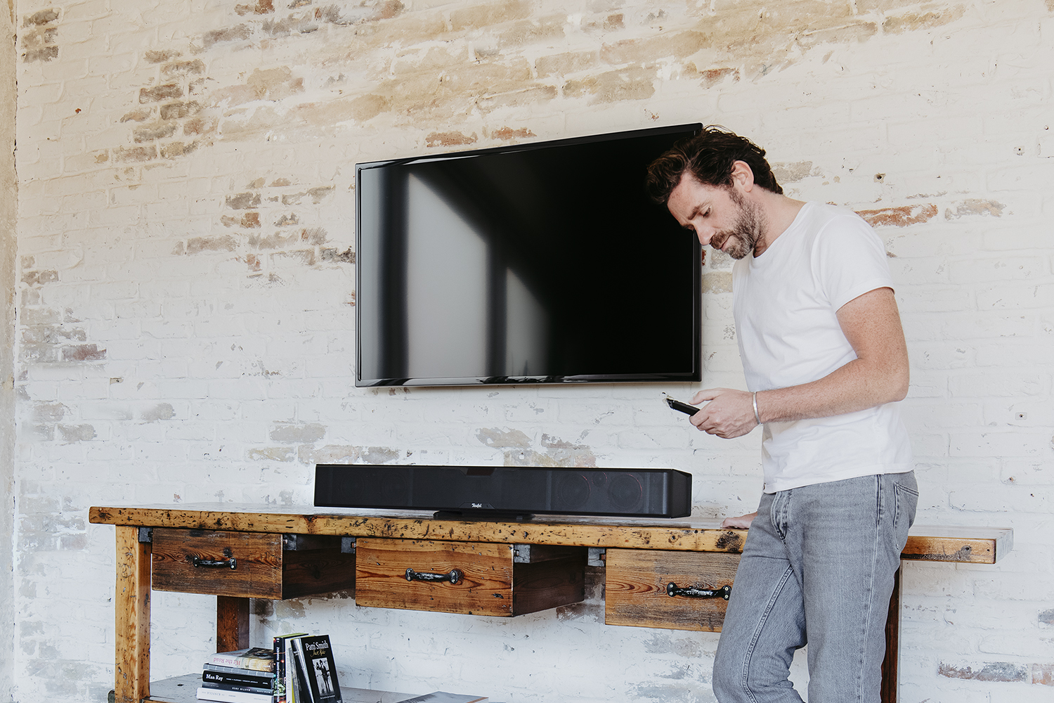 Mann steuert mit Fernbedieung Soundbar CINEBAR PRO