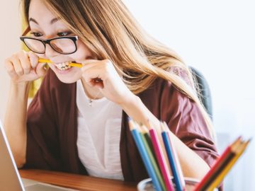 Frau vor Laptop beißt auf Stift