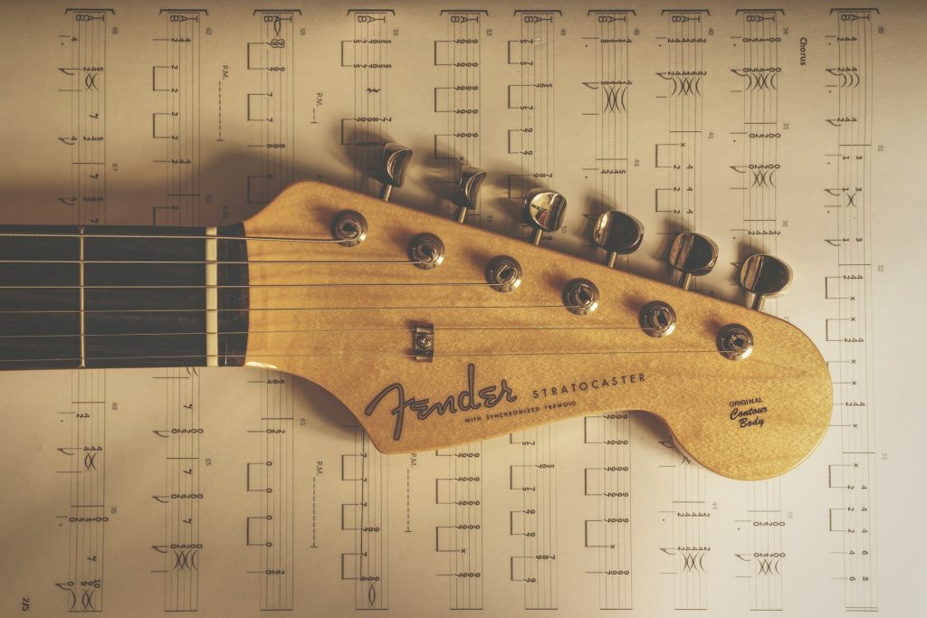 Kopfplatte einer Fender Stratocaster vor einem Notenblatt